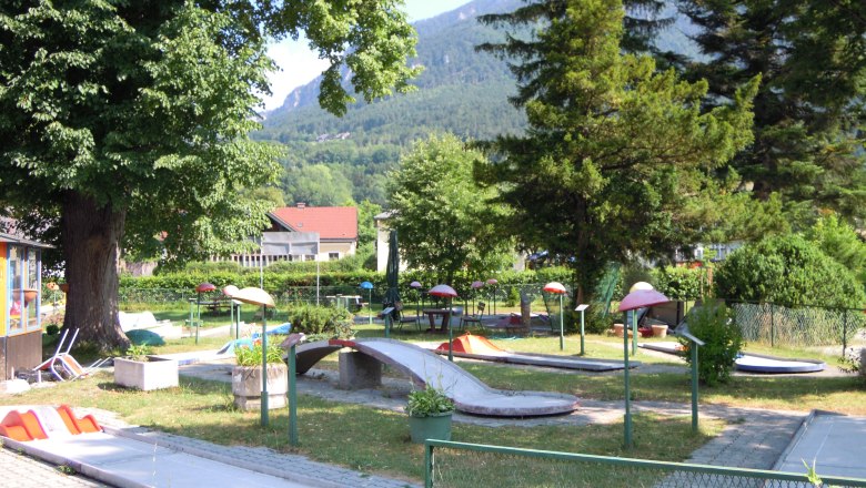 Minigolfplatz in Payerbach mit B&auml;umen und Bergen im Hintergrund.