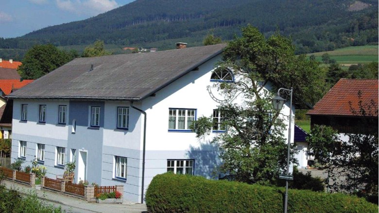 Privatzimmer Familie Karl, © Privatzimmer Familie Karl Ein großes, zweistöckiges, weiß-blaues Haus mit Garten und Berglandschaft im Hintergrund.