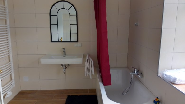 Modernes Badezimmer mit Badewanne, Waschbecken und Spiegel.
