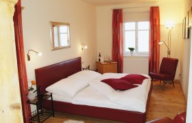 Gem&uuml;tliches Schlafzimmer mit rotem Bett und Dekor.