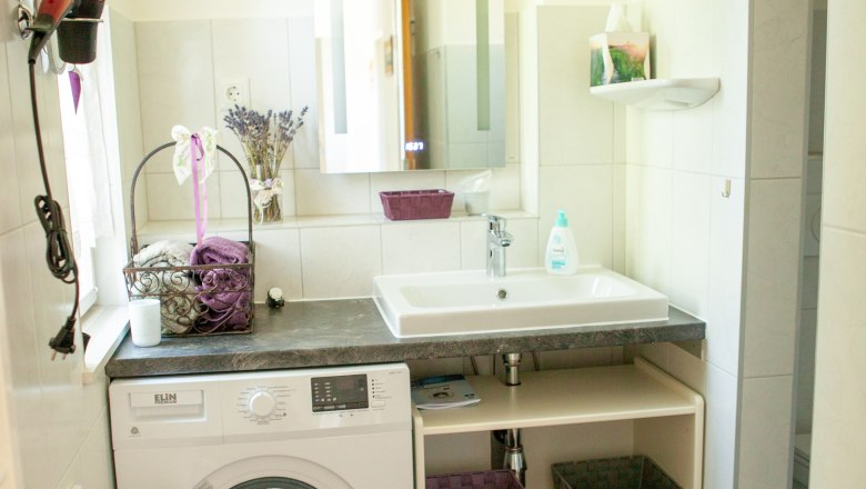 Modernes Badezimmer mit Waschmaschine, Waschbecken und Spiegel.