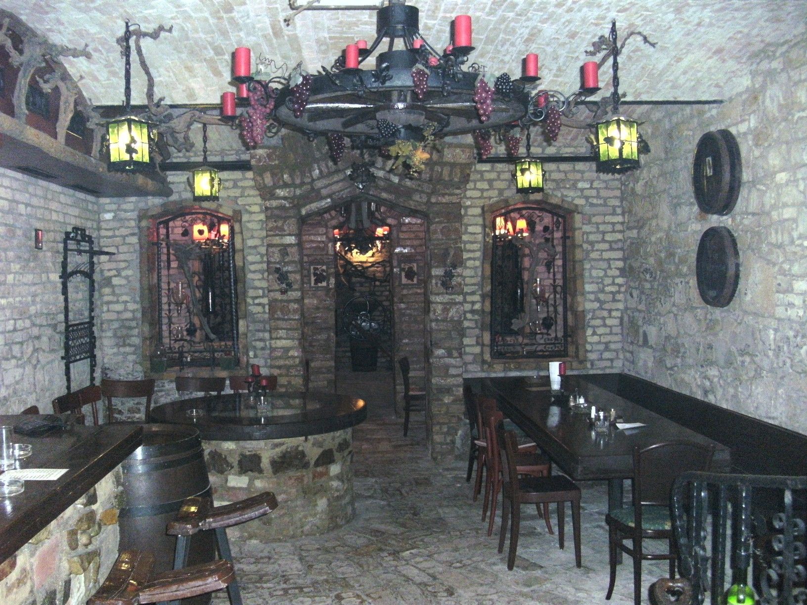 Ein rustikales Heurigenlokal im Keller mit Steinwänden, Holzmöbeln und dekorativen Lichtern.