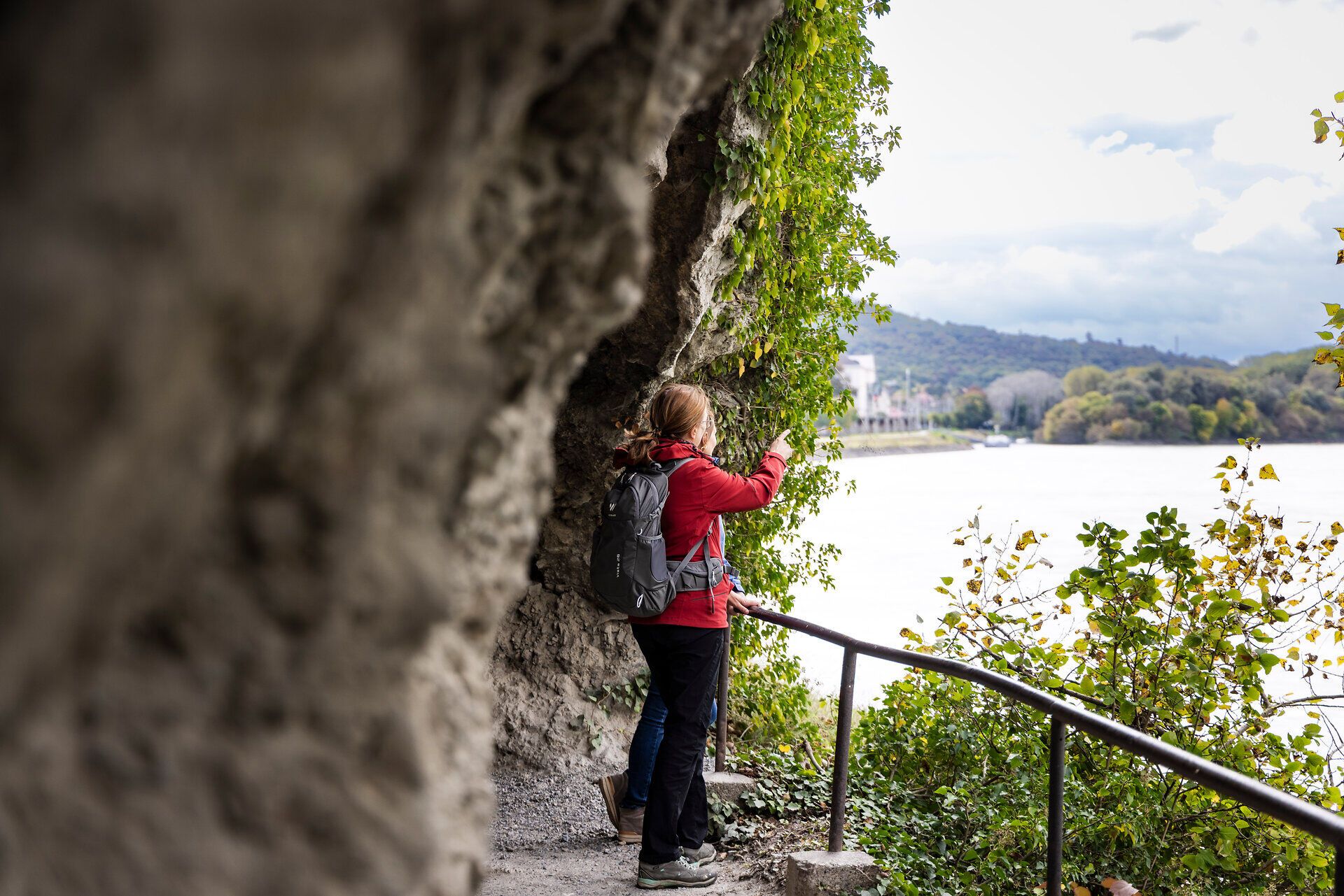 Zwei Frauen auf einem Wanderweg blicken aufs Wasser. Im Hintergrund Felsen. 
