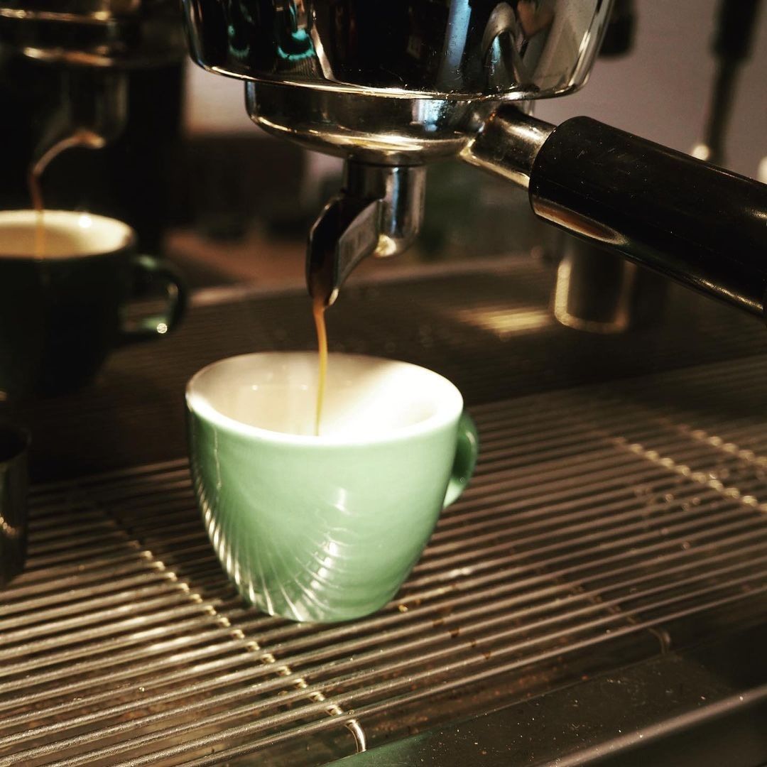 Espressomaschine füllt eine grüne Tasse mit Kaffee.