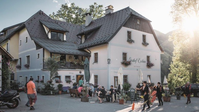 Gasthof Eschau, © Gasthof Eschau Ein traditionelles Gasthaus mit Menschen im Freien bei Sonnenschein.