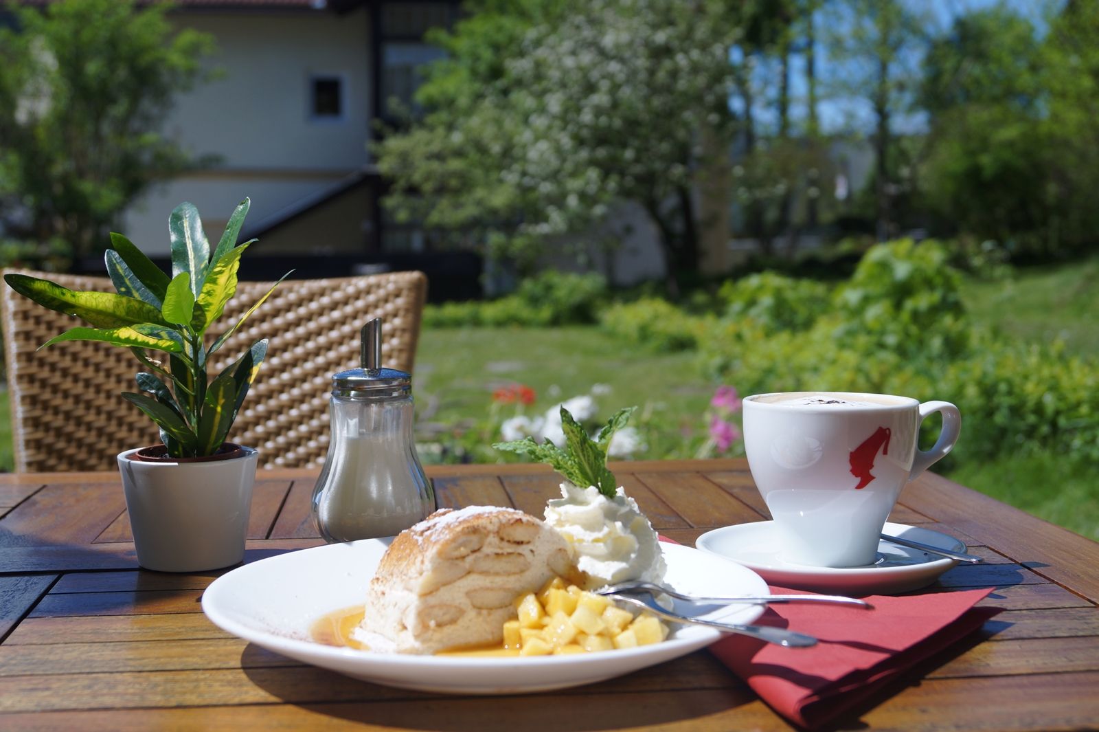 Ein Teller mit Dessert und eine Tasse Kaffee auf einem Tisch im Freien.