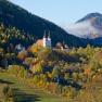 Herbstliche Landschaft mit Kirche in Maria Schutz, umgeben von bunten B&auml;umen und H&uuml;geln.