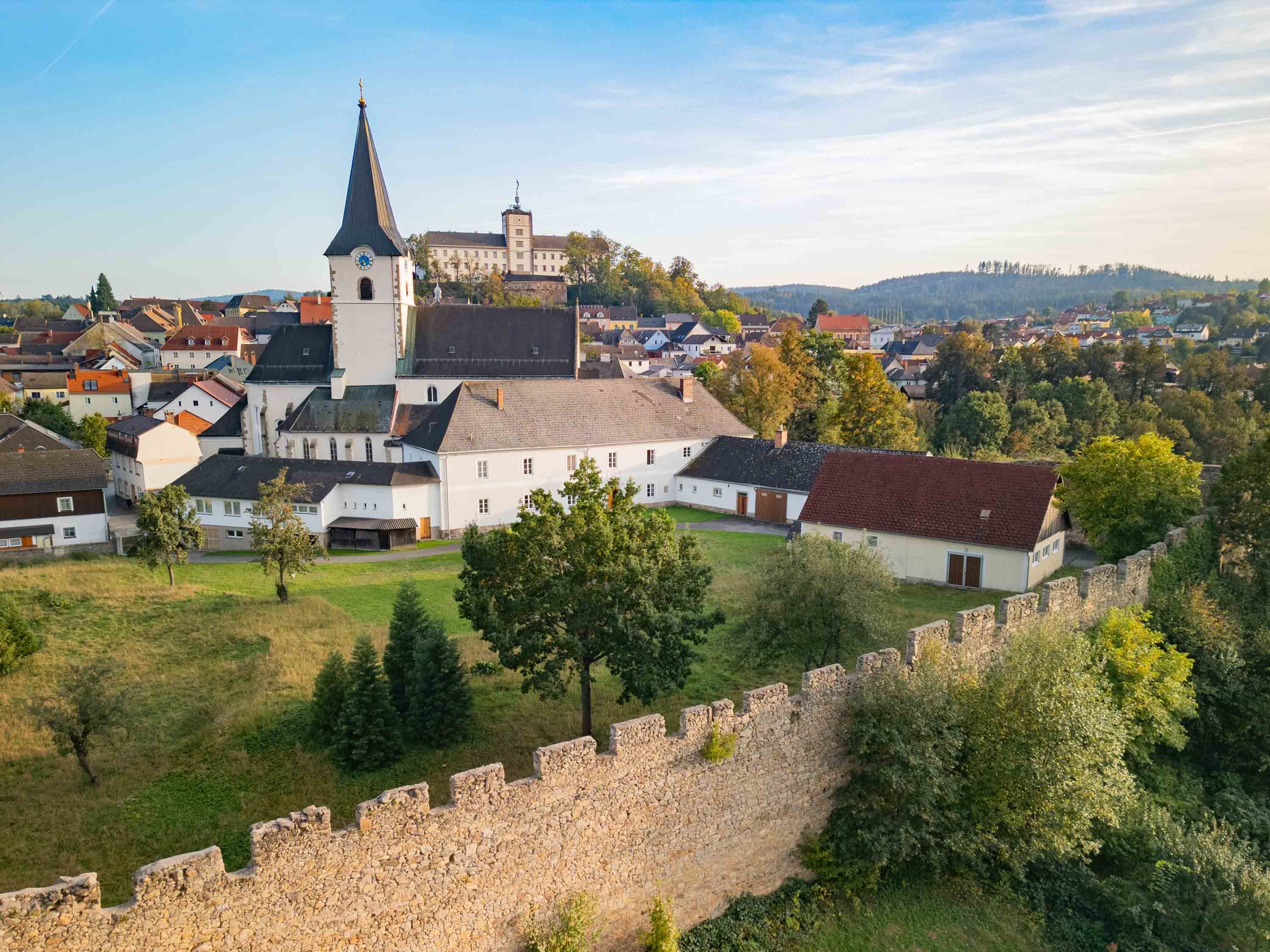 Luftaufnahme einer Stadt mit Kirche und Stadtmauer im Vordergrund.