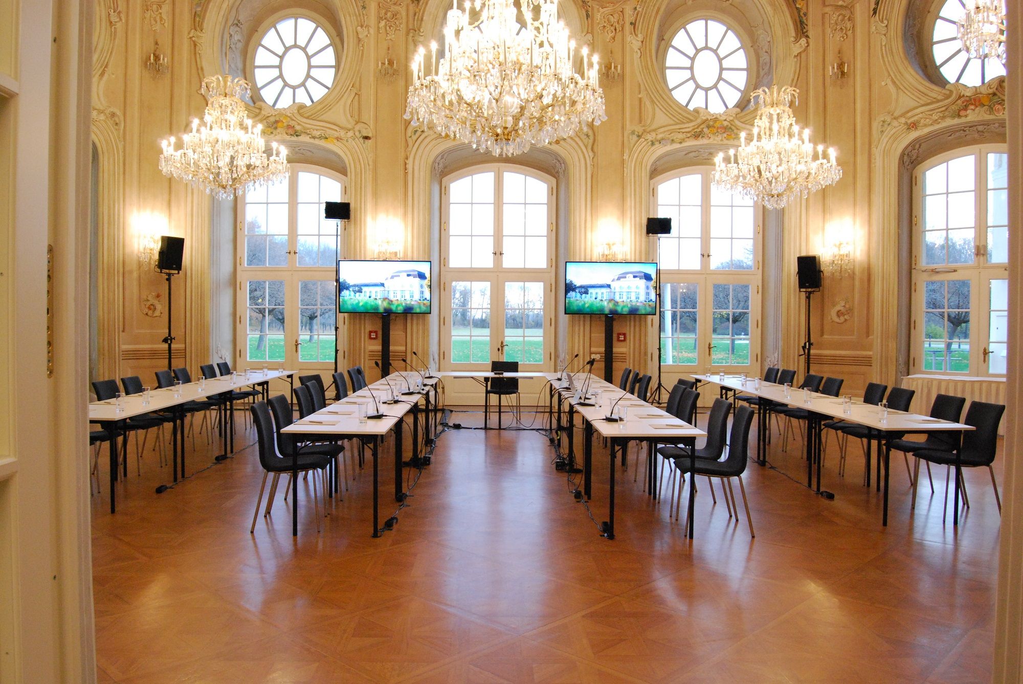 Eleganter Konferenzraum mit Kronleuchtern und großen Fenstern.