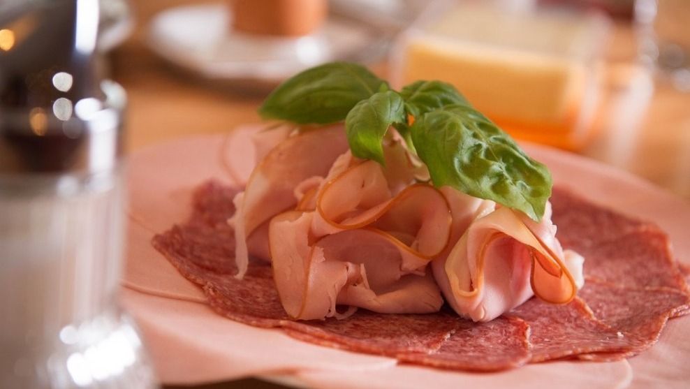 Nahaufnahme einer Wurstplatte mit Schinken, Salami und Basilikum.