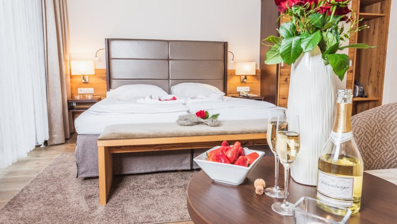Doppelzimmer im Hotel Schneeberghof mit Bett, Rosen, Sekt und Erdbeeren.