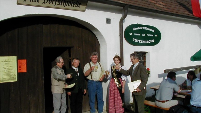 Gruppe von Menschen vor der Alten Dorfschmiede in Totzenbach, die ansto&szlig;en.