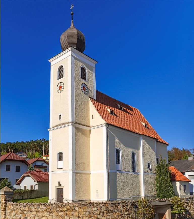 Pfarrkirche Hollenthon mit Zwiebelturm und blauen Himmel.