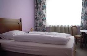 Ein einfach eingerichtetes Hotelzimmer mit Bett, Tisch und Stuhl.