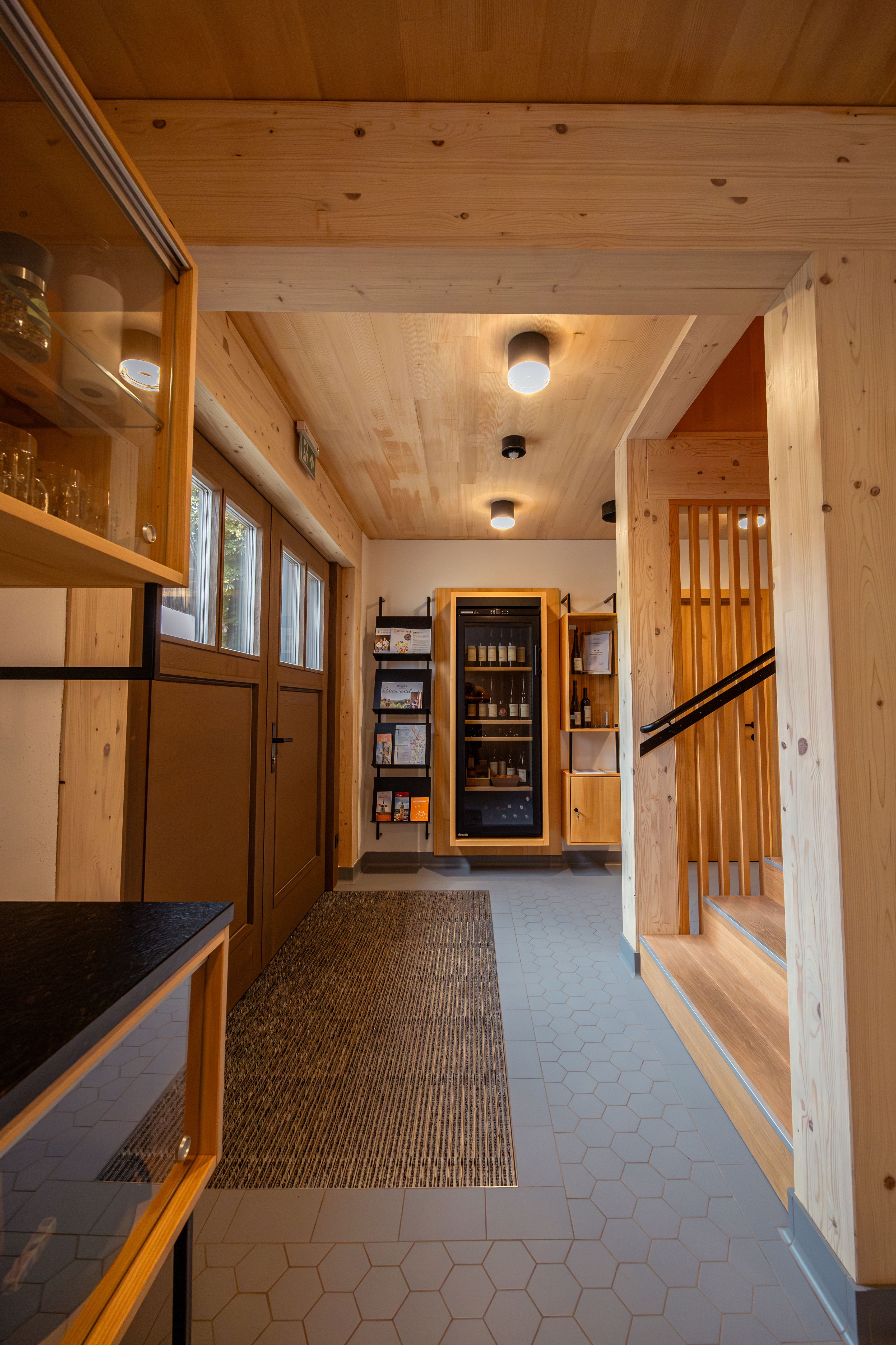 Ein modernes Kellerstöckl im Weinviertel bei Dämmerung, umgeben von Weinreben und einem Garten. Ein Schild zeigt 'Urlaub am Bauernhof'.