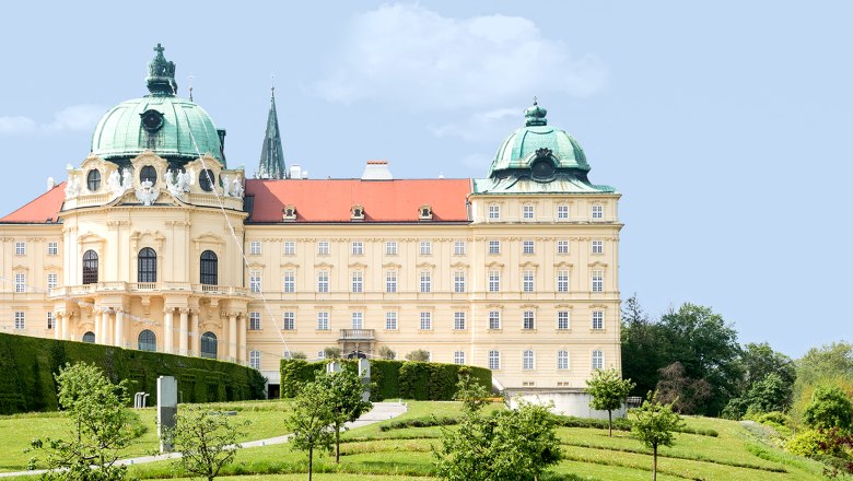 Stift Klosterneuburg mit grünen Kuppeln und gepflegtem Garten im Vordergrund.