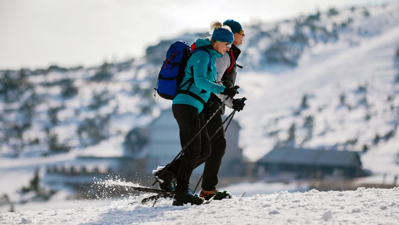 Zwei Personen beim Schneeschuhwandern auf einem verschneiten Berg.