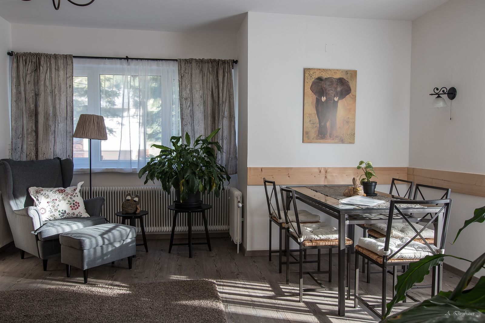 Gemütliches Wohnzimmer mit Sessel, Tisch und Pflanzen.