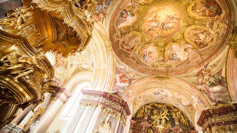 Innenansicht der Basilika Maria Taferl mit reich verzierten goldenen Elementen und Fresken an der Decke.