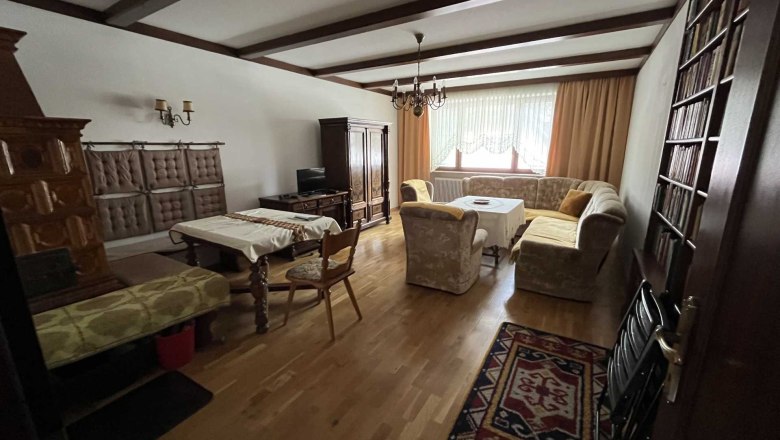 Wohnzimmer mit Holzboden, Sofa, Tisch, Schrank und Kamin.