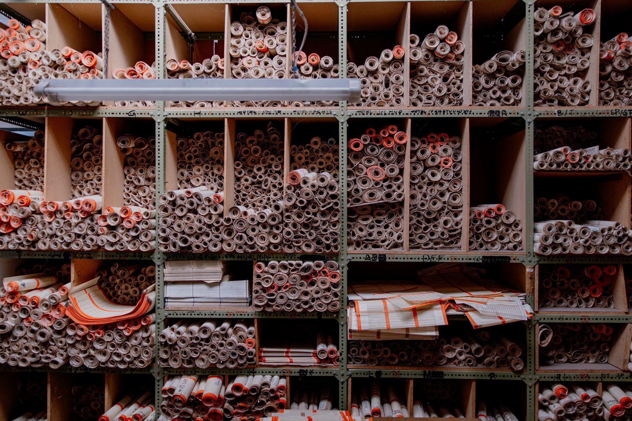 Regal mit vielen gerollten Papierdokumenten in Fächern.