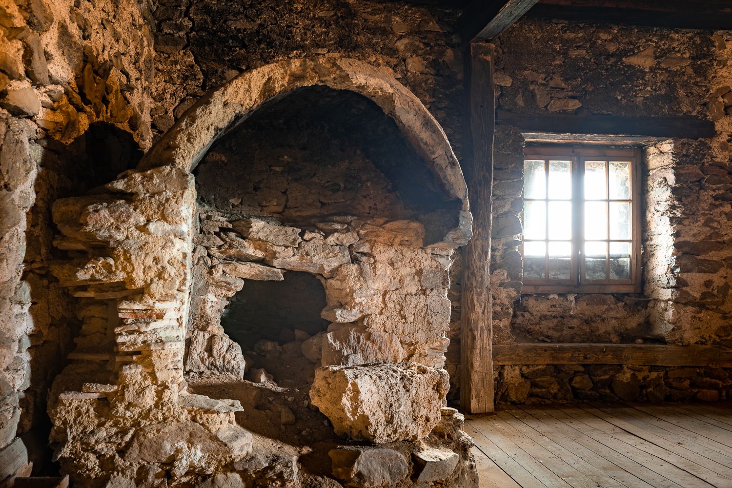 Alter Backofen in einem steinernen Raum mit Holzboden und Fenster. Befindet sich im Dachgeschoss der Wehrkirche Lichtenegg.
