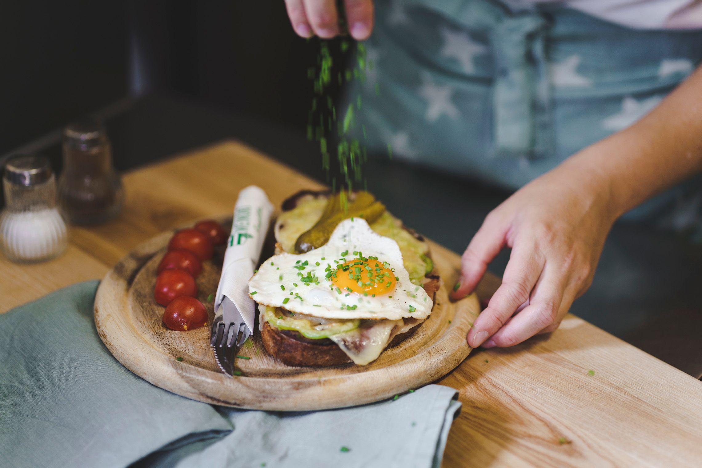 Ein Teller mit einem belegten Brot, Spiegelei und Tomaten, garniert mit Schnittlauch.