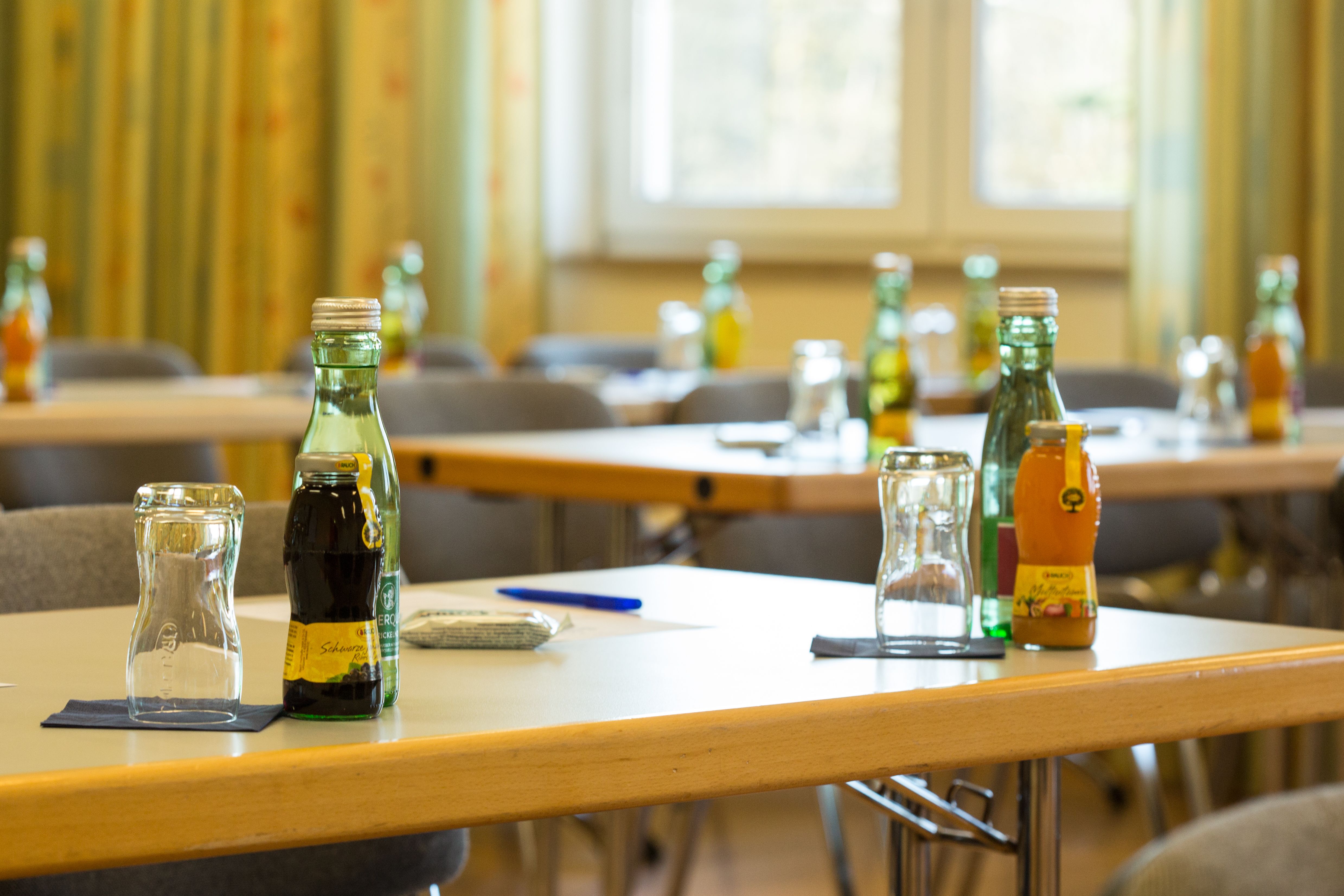 Ein Seminarraum mit Tischen, auf denen Getränke und Gläser stehen.
