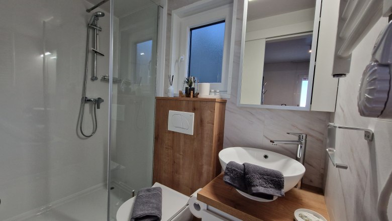 Modernes Badezimmer mit Dusche, Waschbecken und Toilette.