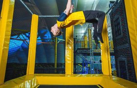 Person macht einen Rückwärtssalto auf einem Trampolin in einer Halle.