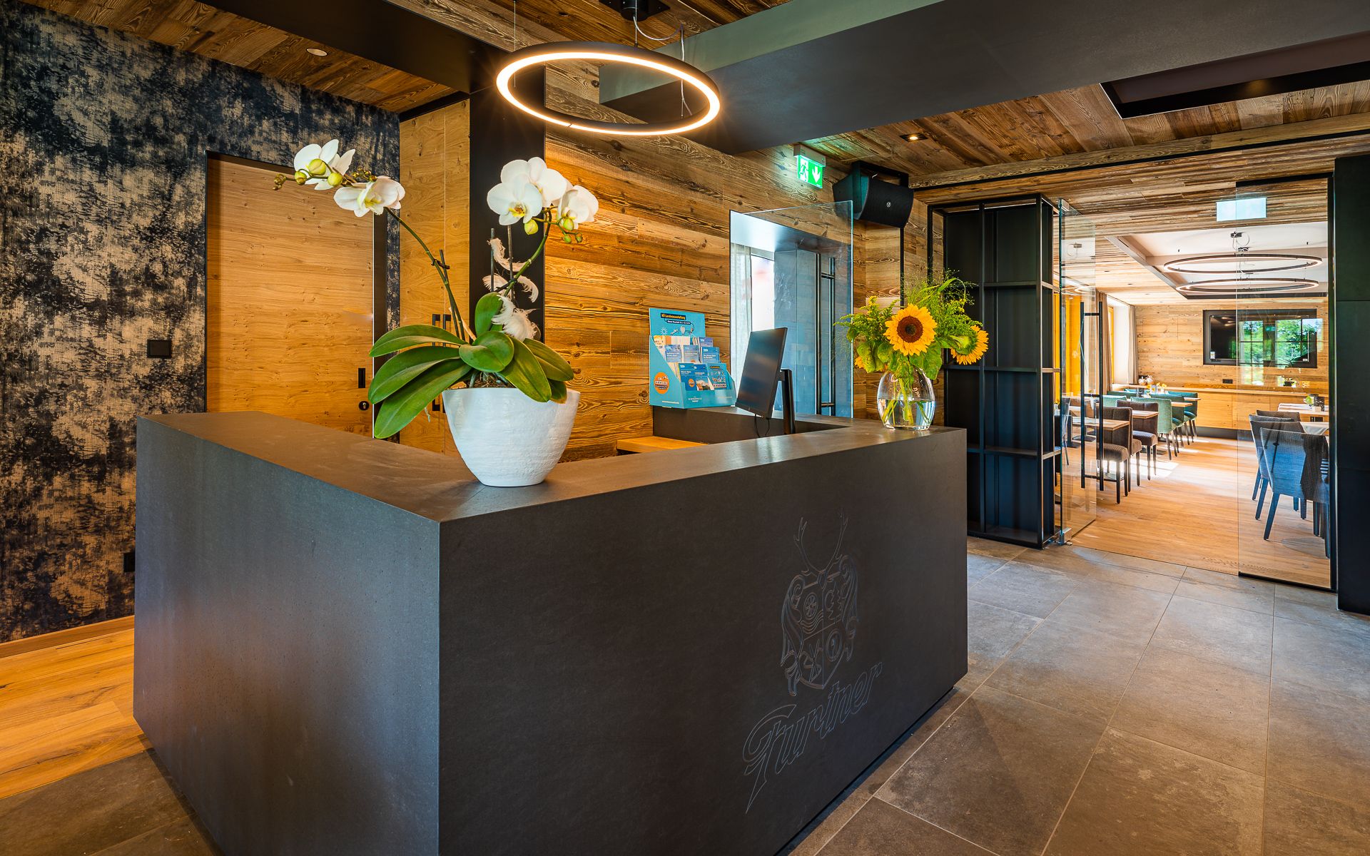 Moderne Rezeption mit Holzverkleidung, Orchideen und Sonnenblumen auf dem Tresen.