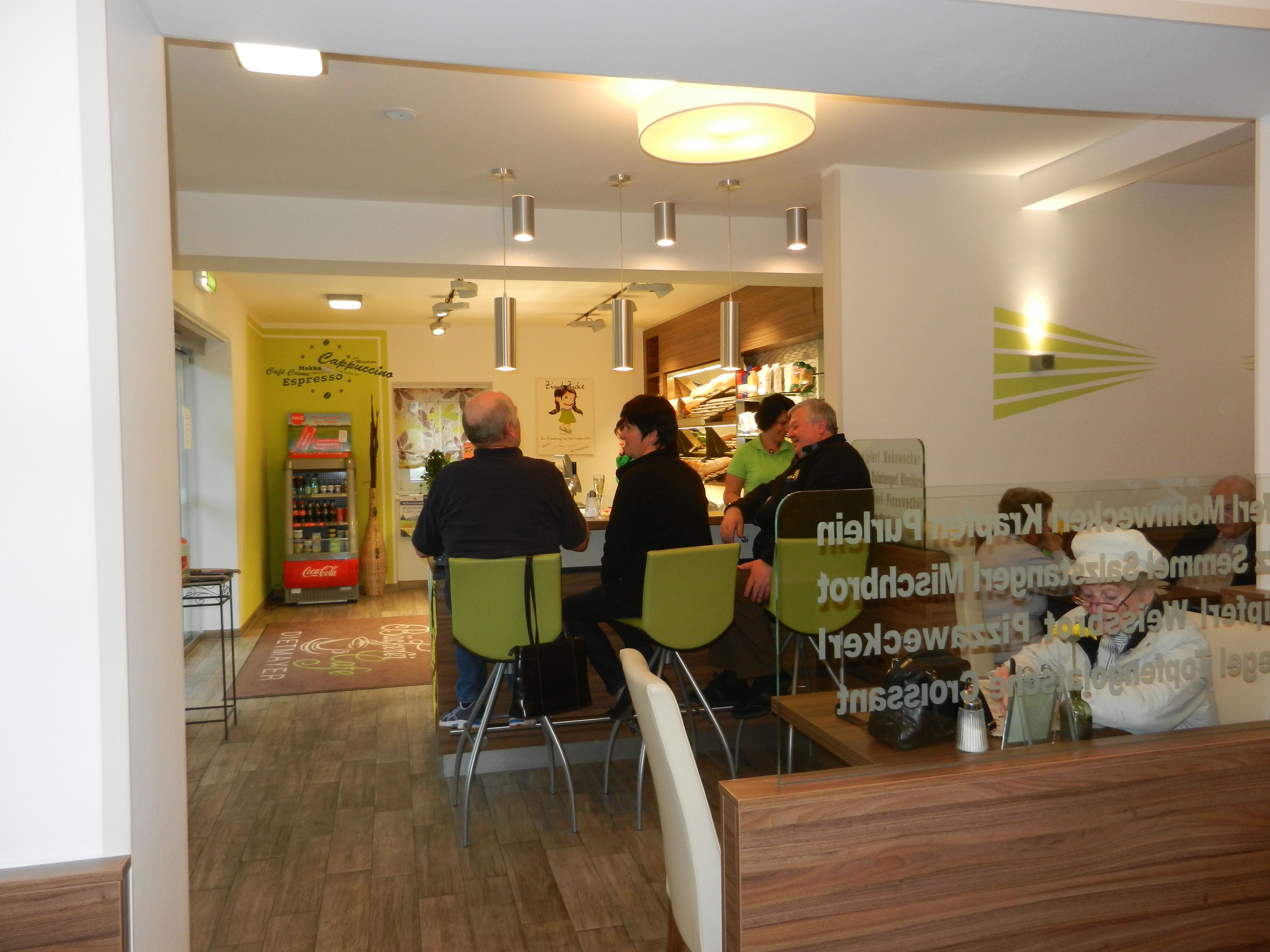 Innenansicht eines Cafés mit mehreren Personen an einem Tisch.