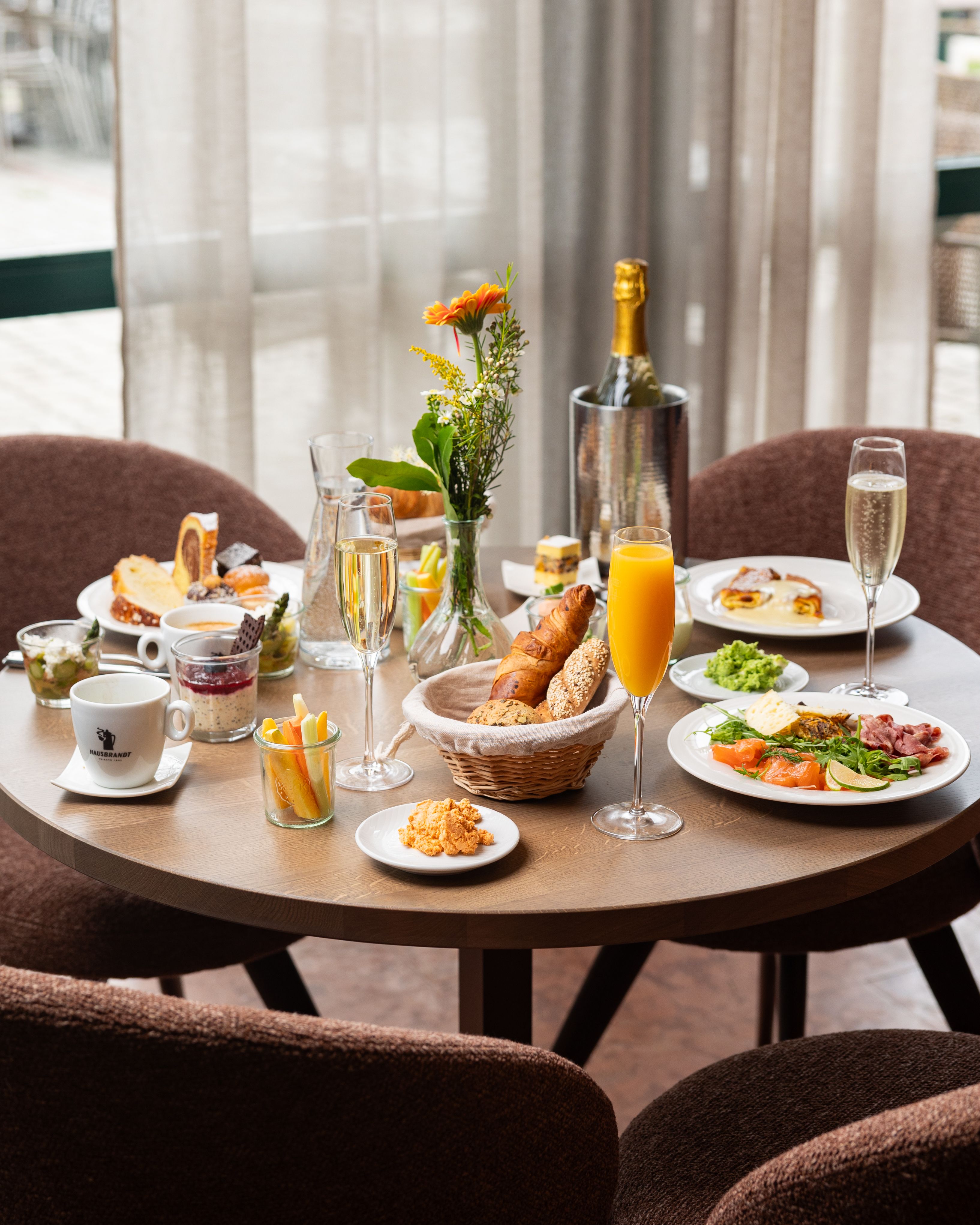 Ein gedeckter Frühstückstisch mit verschiedenen Speisen, Getränken und Blumen.