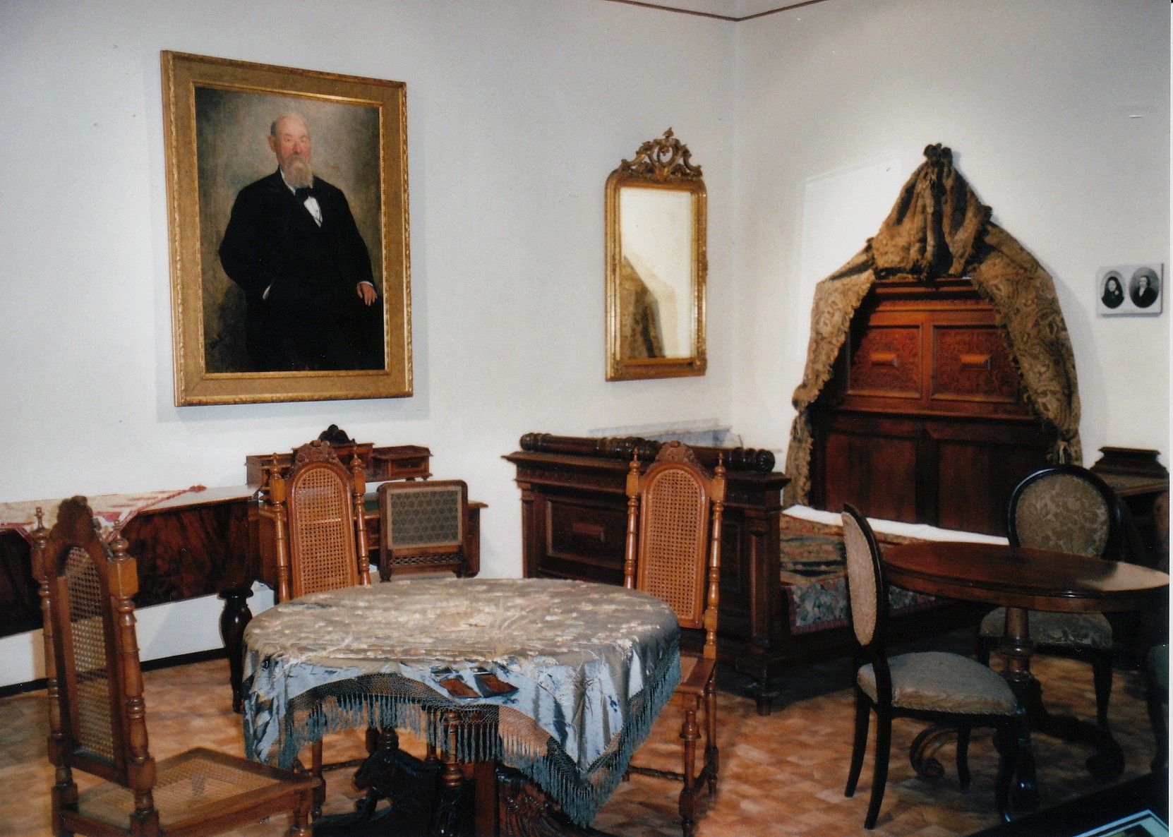 Historischer Raum mit antiken Möbeln und Gemälde eines Mannes an der Wand.