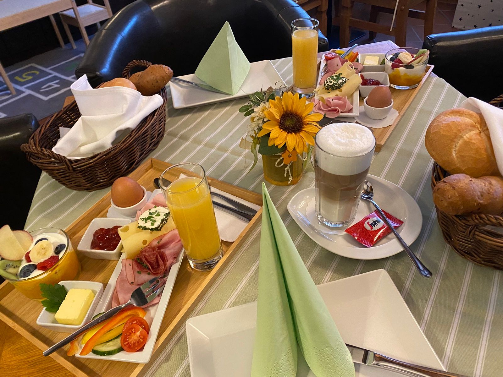 Ein gedeckter Frühstückstisch mit Brötchen, Aufschnitt, Eiern, Saft und Kaffee in einer Pension.
