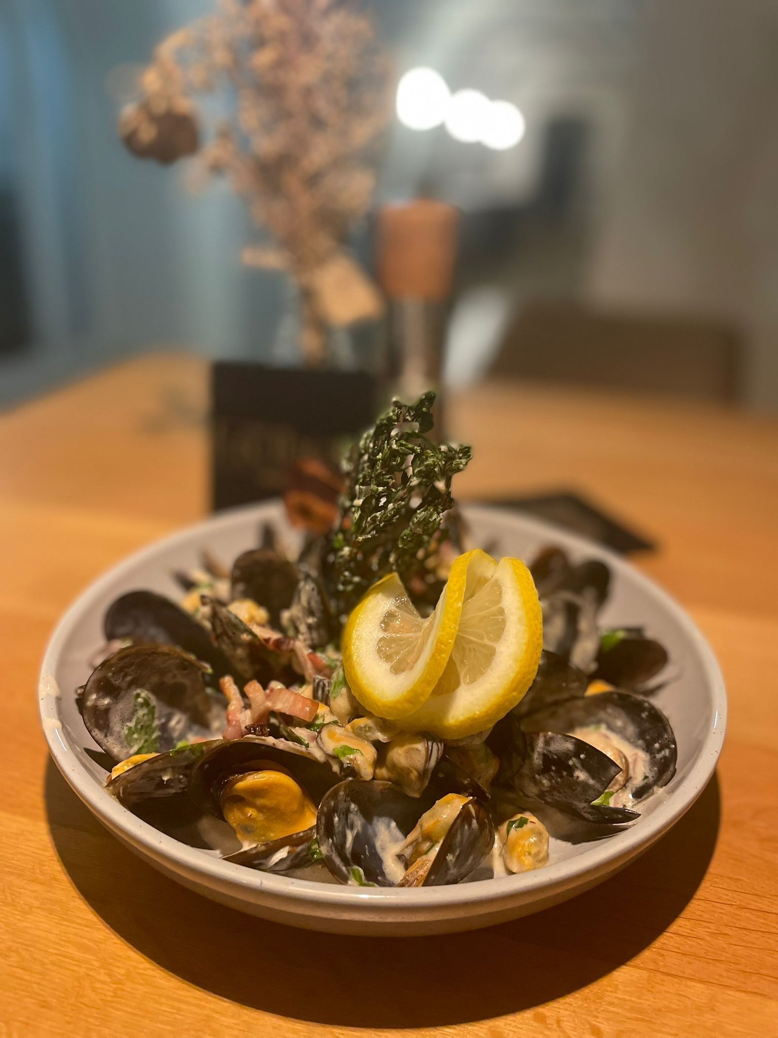 Ein Teller mit Muscheln, Sahnesoße und Zitronenscheiben auf einem Holztisch.