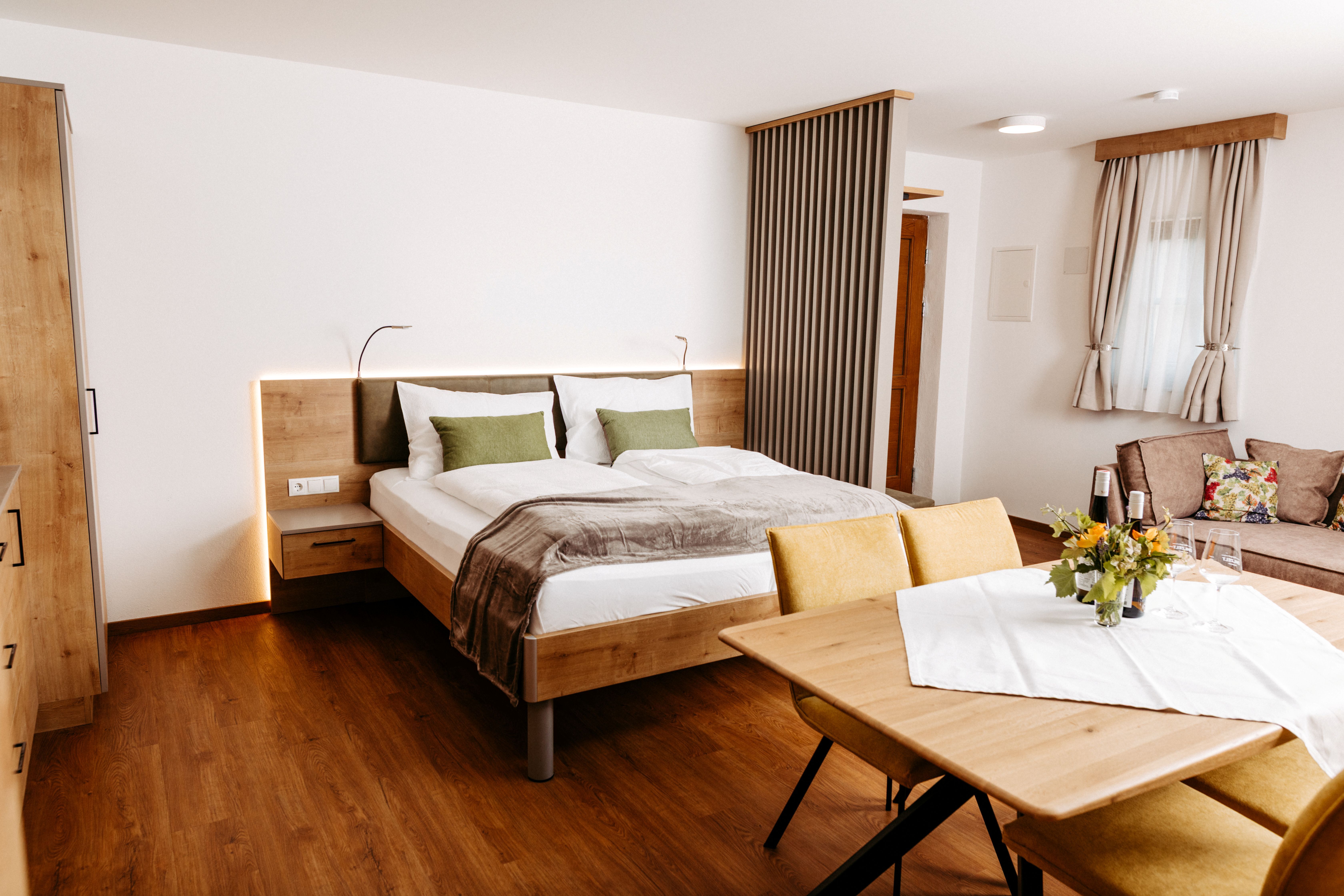 Modernes, helles Doppelzimmer mit Sitzbereich und Holzmöbeln in einer stilvollen Unterkunft am Wagram.