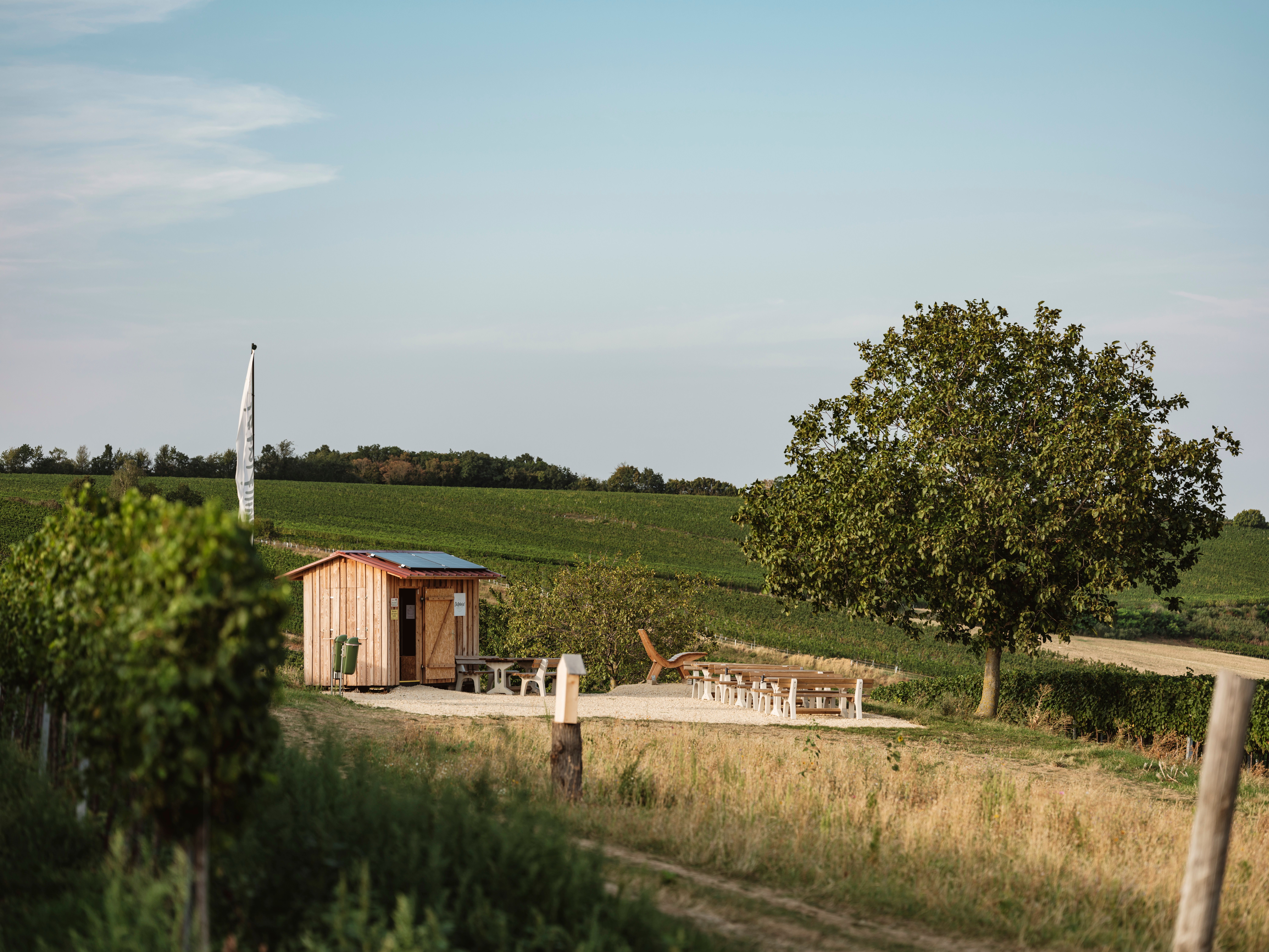 Eine kleine Holzhütte mit Sitzgelegenheiten in einer ländlichen Landschaft.