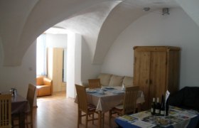 Ein Wohnzimmer mit Gew&ouml;lbedecke, Esstisch, St&uuml;hlen und einem Schrank.