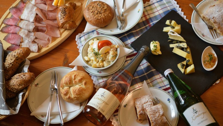 Ein Tisch mit einer Auswahl an Wurst, K&auml;se, Brot, Salat und Getr&auml;nken.