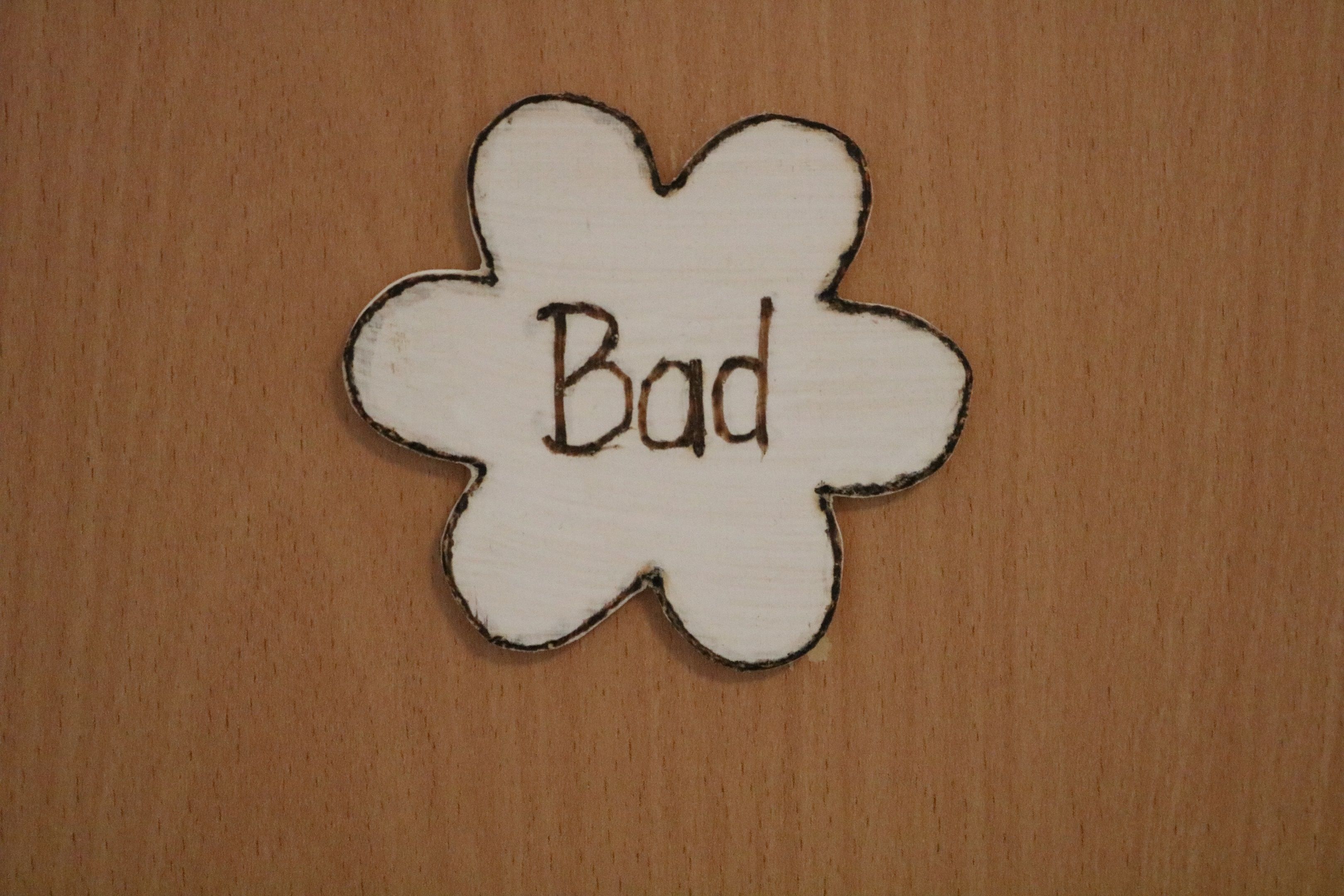 Holzschild in Blumenform mit der Aufschrift 'Bad'.