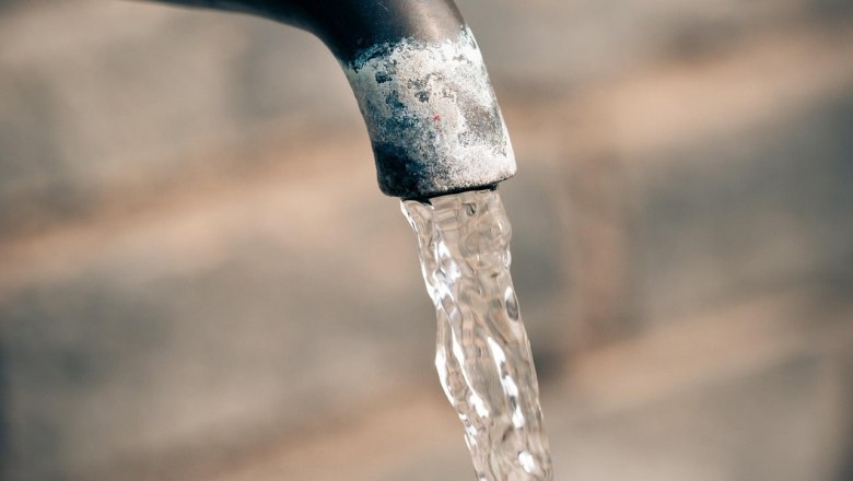 Nahaufnahme eines Wasserhahns mit flie&szlig;endem Wasser vor unscharfem Hintergrund.