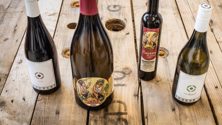 Vier Weinflaschen auf einem Holztisch.