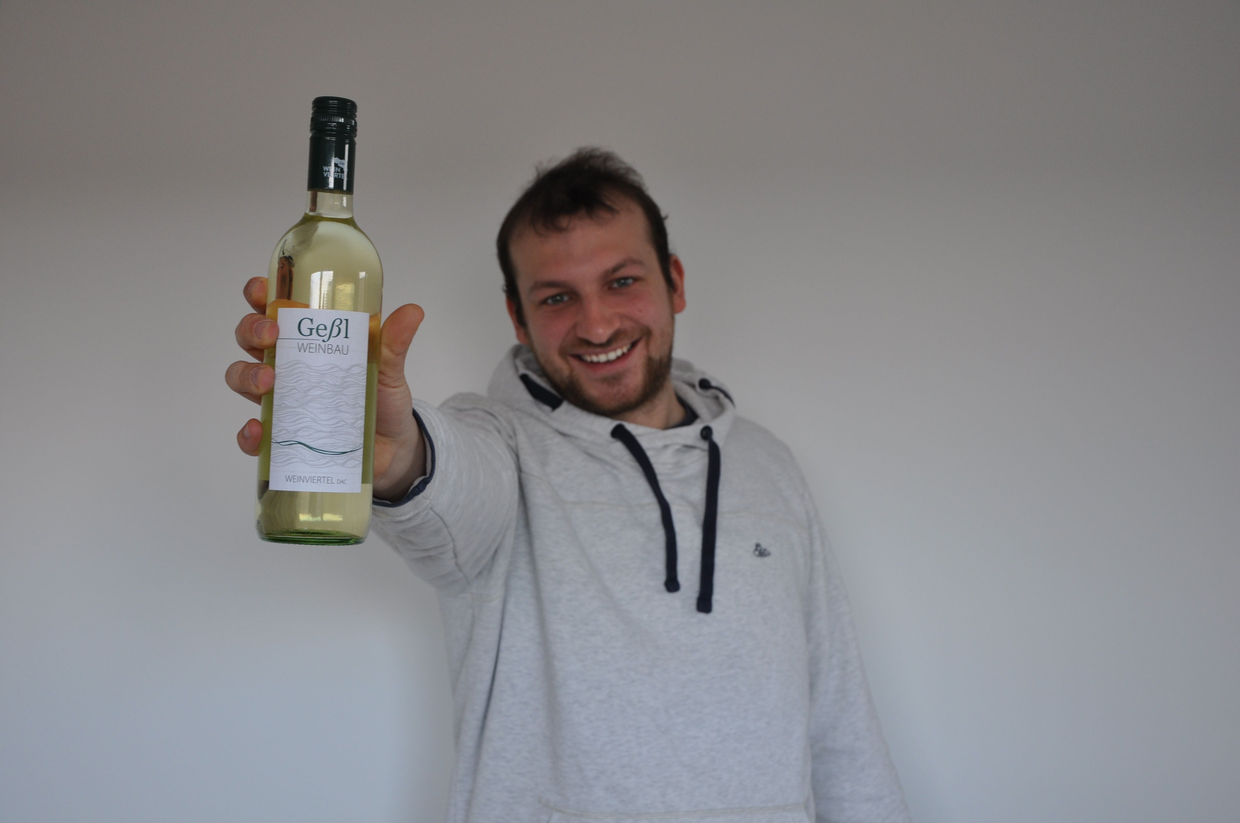 Mann hält eine Flasche Geßl Weinbau Weißwein in die Kamera.
