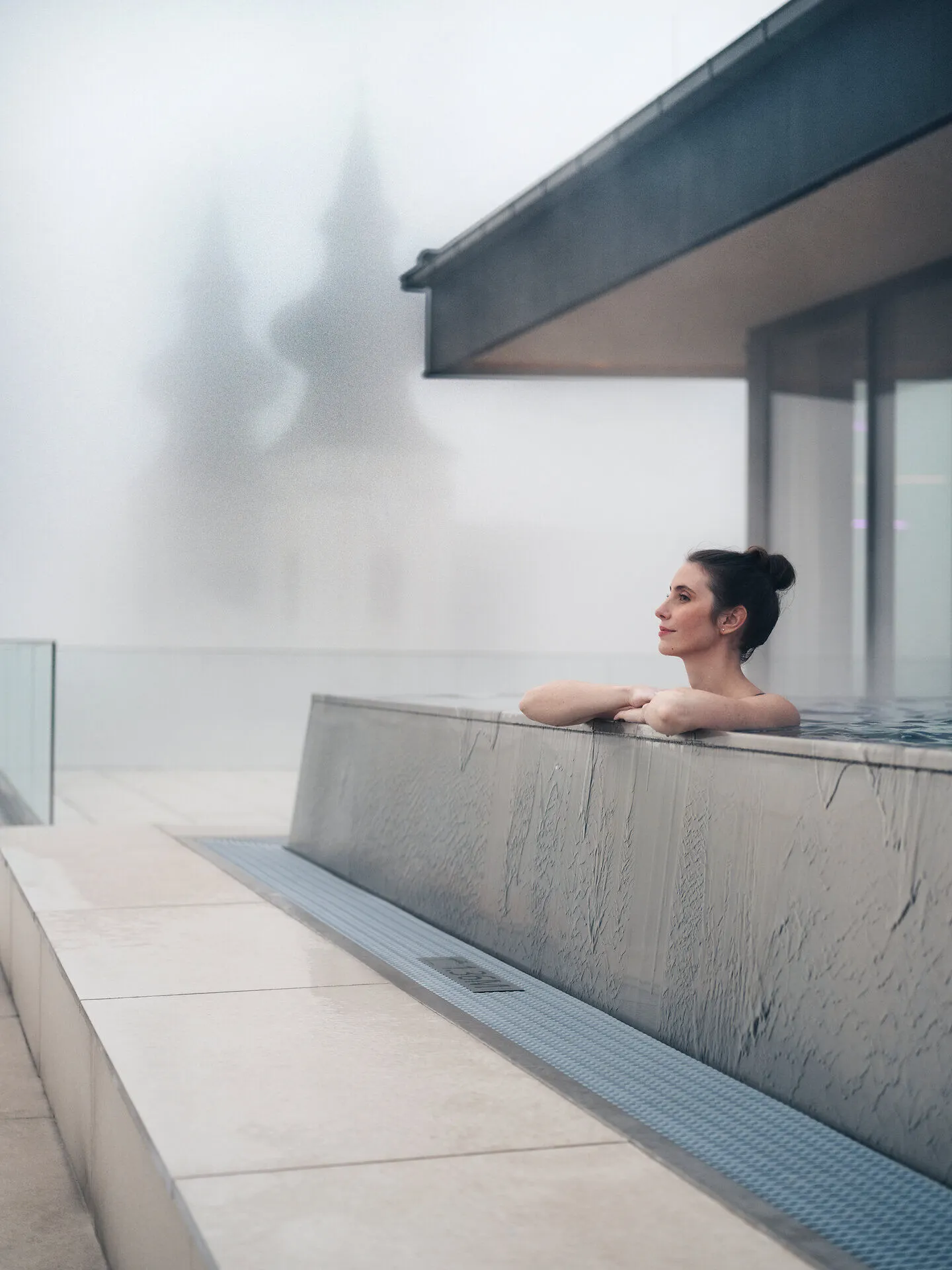 In einem stilvollen Infinity-Pool entspannen Sie und genießen den Blick auf die sanften Hügel, die in mystischen Nebel gehüllt sind. Die ruhige Atmosphäre lädt dazu ein, die Seele baumeln zu lassen und die Schönheit der Natur zu erleben.
