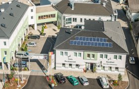 Luftaufnahme eines Gebäudekomplexes mit dem Gasthof zum Alten Brauhaus, Solarpanels auf dem Dach und mehreren geparkten Autos.