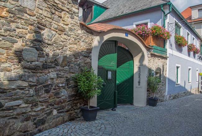 Historisches Geb&auml;ude mit gr&uuml;nem Tor und Blumen.