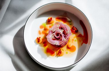 Speisenfoto Fisch und Fermentiertes als Rose auf weißem Teller angerichtet