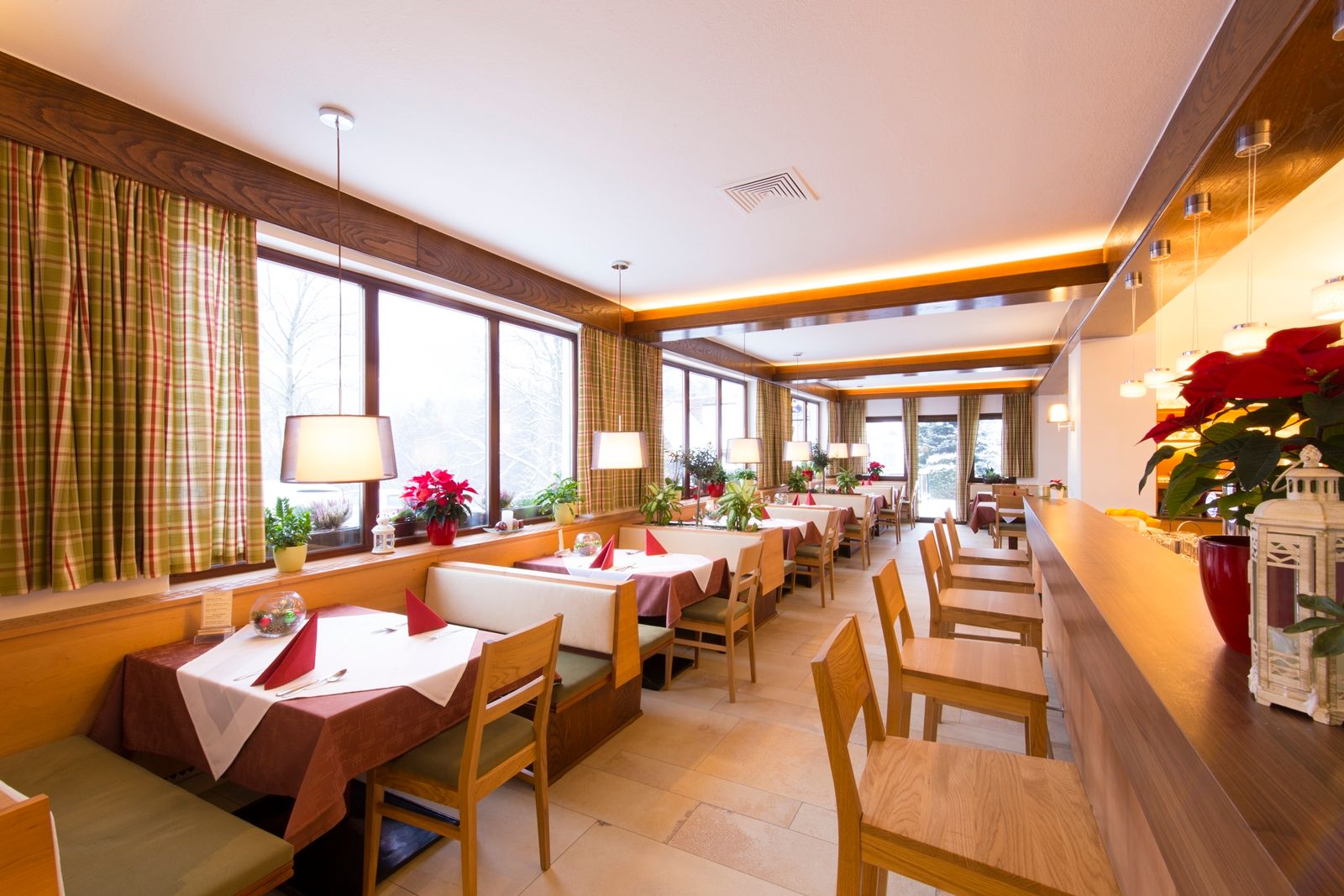 Innenansicht eines gemütlichen Restaurants mit Holzmöbeln und großen Fenstern.