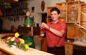 Ein Mann zapft Bier an einer Theke in einem Gasthof.